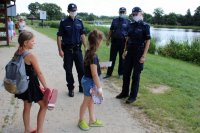 policjanci rozmawiają z dziećmi odpoczywającymi nad zalewem