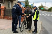 policjanci wraz z pracownikiem UG w Miedźnie wręczają rowerzyście odblaski i lampki rowerowe