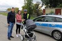 policjantka wraz z pracownikiem UG w Miedźnie wręczają pieszej, która prowadzi wózek z dzieckiem odblaski