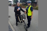 policjantka wręcza rowerzyście odblaski i lampki rowerowe