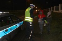 policjant rozdaje dzieciom-chłopcu i dziewczynce opaski odblaskowe