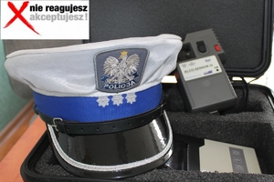 Zdjęcie przedstawia policyjną czapkę oraz alkocensor. W lewym górnym rogu napis: nie reagujesz -  akceptujesz.