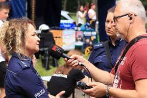 Zdjęcie przedstawia policjantkę udzielającą wywiadu dziennikarzowi radiowemu.