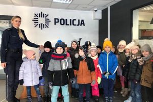 Zdjęcie przedstawia policjantkę oraz grupę dzieci pozujących do zdjęcia.
