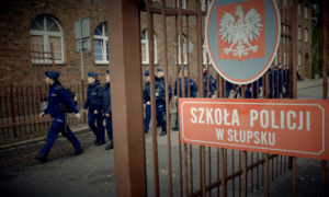 Napis Szkoła Policji w Słupsku i maszerujący policjanci.