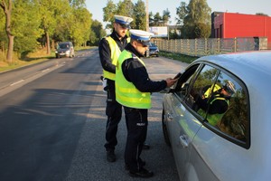Zdjęcie przedstawia policjantów ruchu drogowego, którzy sprawdzają stan trzeźwości kierowcy pojazdu osobowego.